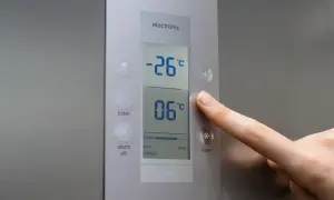 Palec naciska przycisk "super" na panelu zamrażarki, pokazując jaka temperatura w zamrażarce wynosi -26°C.