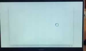 Jasny, biały ekran laptopa z niebieskim kółkiem ładowania pośrodku. Czekam na zakończenie procesu.