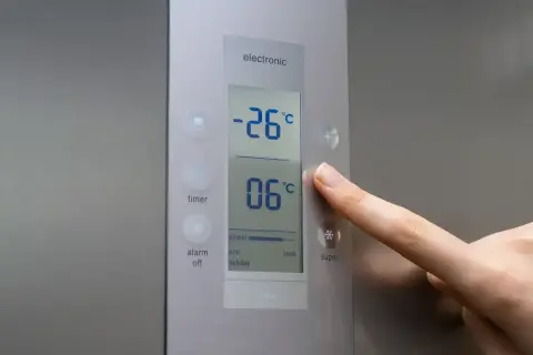 Palec naciska przycisk "super" na panelu zamrażarki, pokazując jaka temperatura w zamrażarce wynosi -26°C.