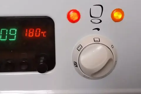 Cyfrowy wyświetlacz piekarnika Mastercook pokazuje 180°C. Pokrętła sterujące i kontrolki są widoczne.