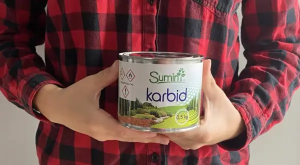 Osoba w koszuli w kratę trzyma puszkę z napisem "Sumin karbid". Szukasz gdzie kupić karbid?