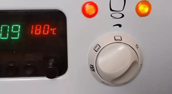 Cyfrowy wyświetlacz piekarnika Mastercook pokazuje 180°C. Pokrętła sterujące i kontrolki są widoczne.