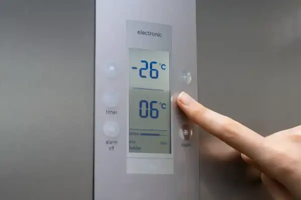 Palec naciska przycisk "super" na panelu zamrażarki, pokazując jaka temperatura w zamrażarce wynosi -26°C.